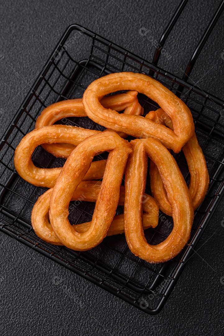 Deliciosos churos doces com açúcar de confeiteiro e creme dentro sobre um fundo escuro de concreto. Prato de fast-food