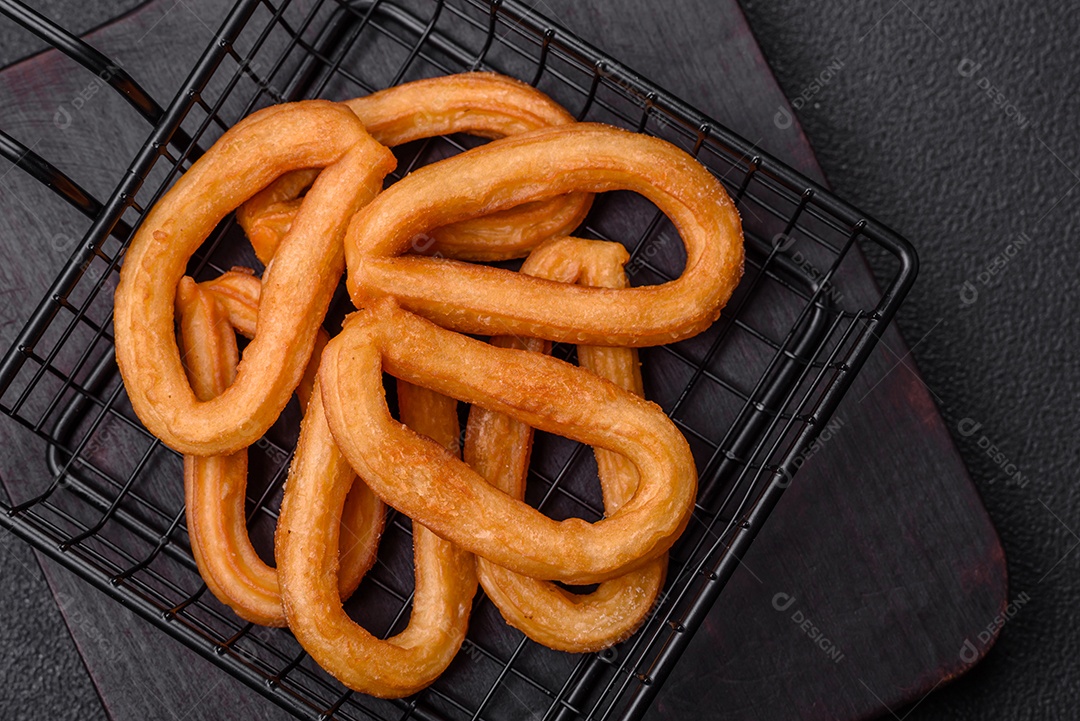 Deliciosos churos doces com açúcar de confeiteiro e creme dentro sobre um fundo escuro de concreto. Prato de fast-food