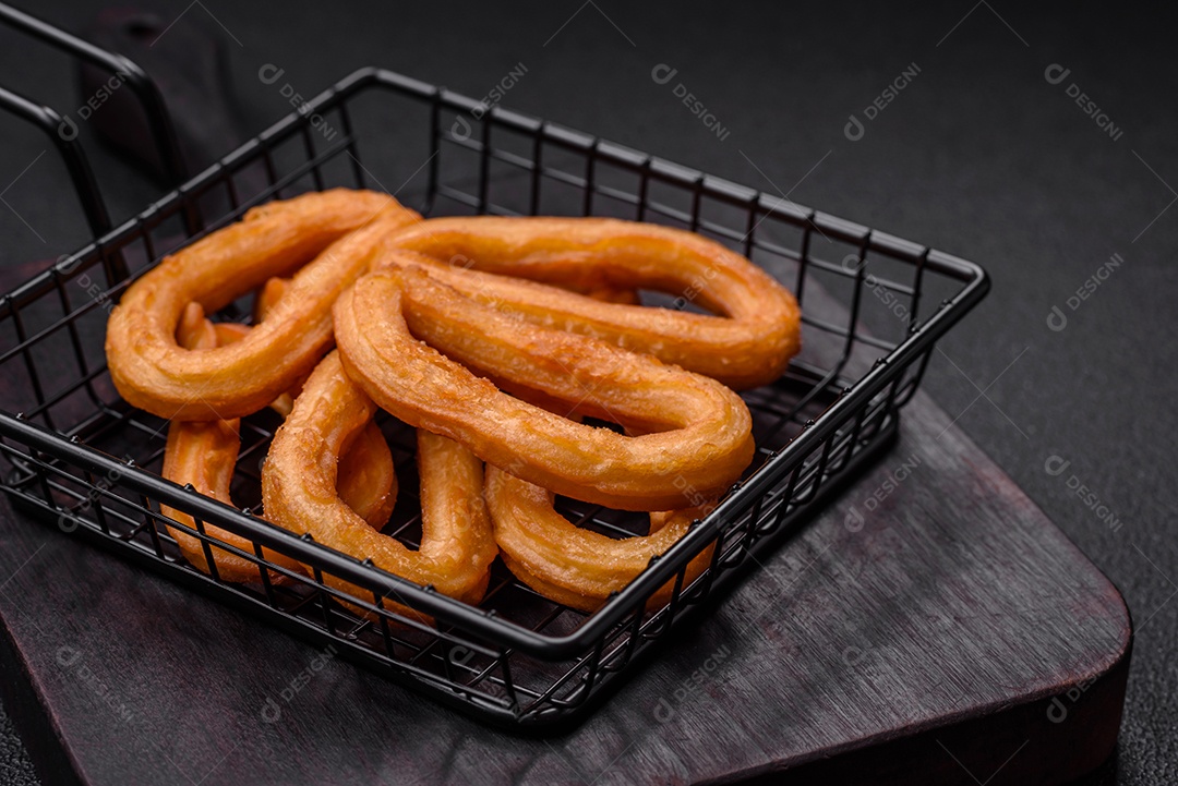 Deliciosos churos doces com açúcar de confeiteiro e creme dentro sobre um fundo escuro de concreto. Prato de fast-food