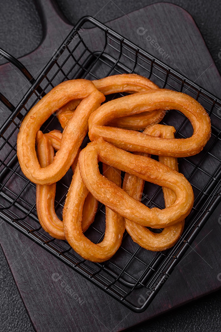 Deliciosos churos doces com açúcar de confeiteiro e creme dentro sobre um fundo escuro de concreto. Prato de fast-food