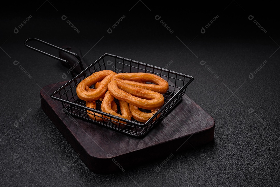 Deliciosos churos doces com açúcar de confeiteiro e creme dentro sobre um fundo escuro de concreto. Prato de fast-food