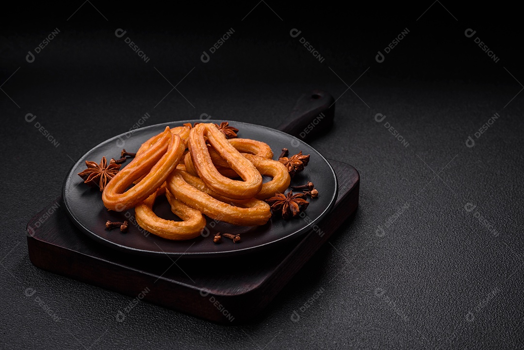 Deliciosos churos doces com açúcar de confeiteiro e creme dentro sobre um fundo escuro de concreto. Prato de fast-food