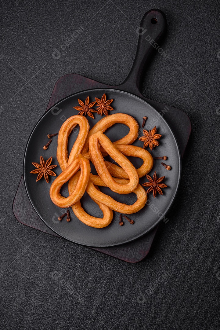 Deliciosos churos doces com açúcar de confeiteiro e creme dentro sobre um fundo escuro de concreto. Prato de fast-food