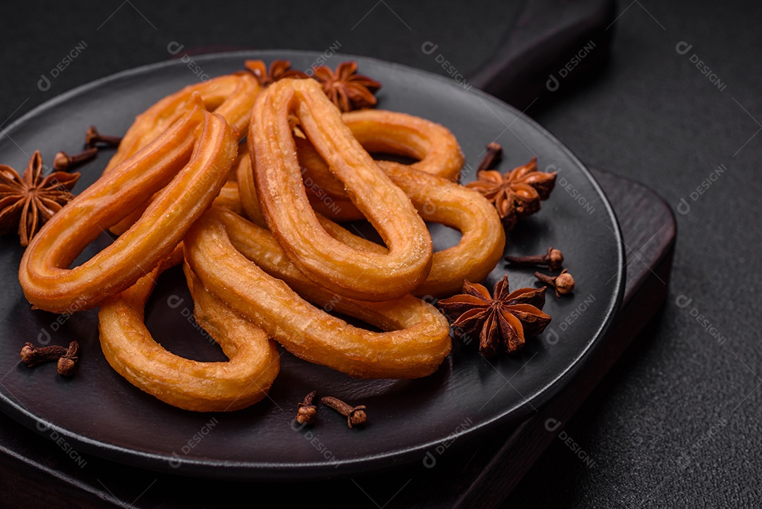 Deliciosos churos doces com açúcar de confeiteiro e creme dentro sobre um fundo escuro de concreto. Prato de fast-food