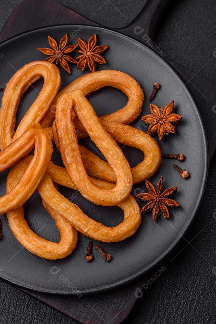 Deliciosos churos doces com açúcar de confeiteiro e creme dentro sobre um fundo escuro de concreto. Prato de fast-food
