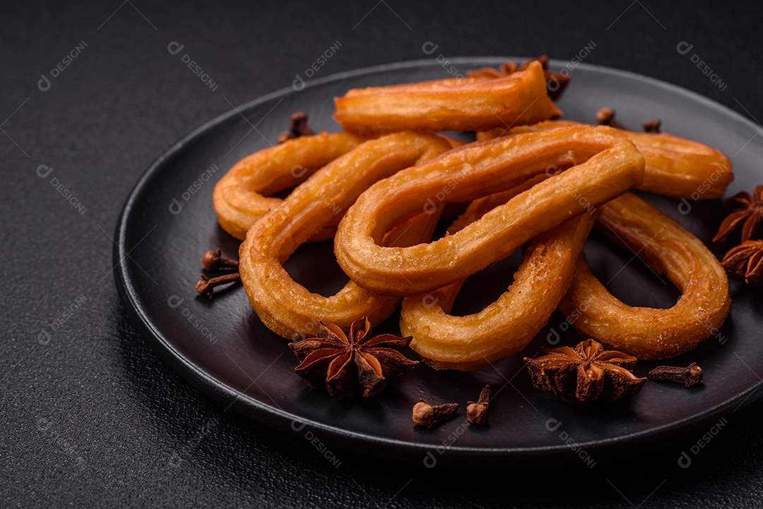 Deliciosos churos doces com açúcar de confeiteiro e creme dentro sobre um fundo escuro de concreto. Prato de fast-food