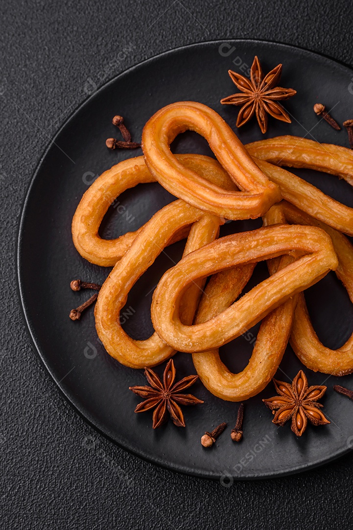 Deliciosos churos doces com açúcar de confeiteiro e creme dentro sobre um fundo escuro de concreto. Prato de fast-food