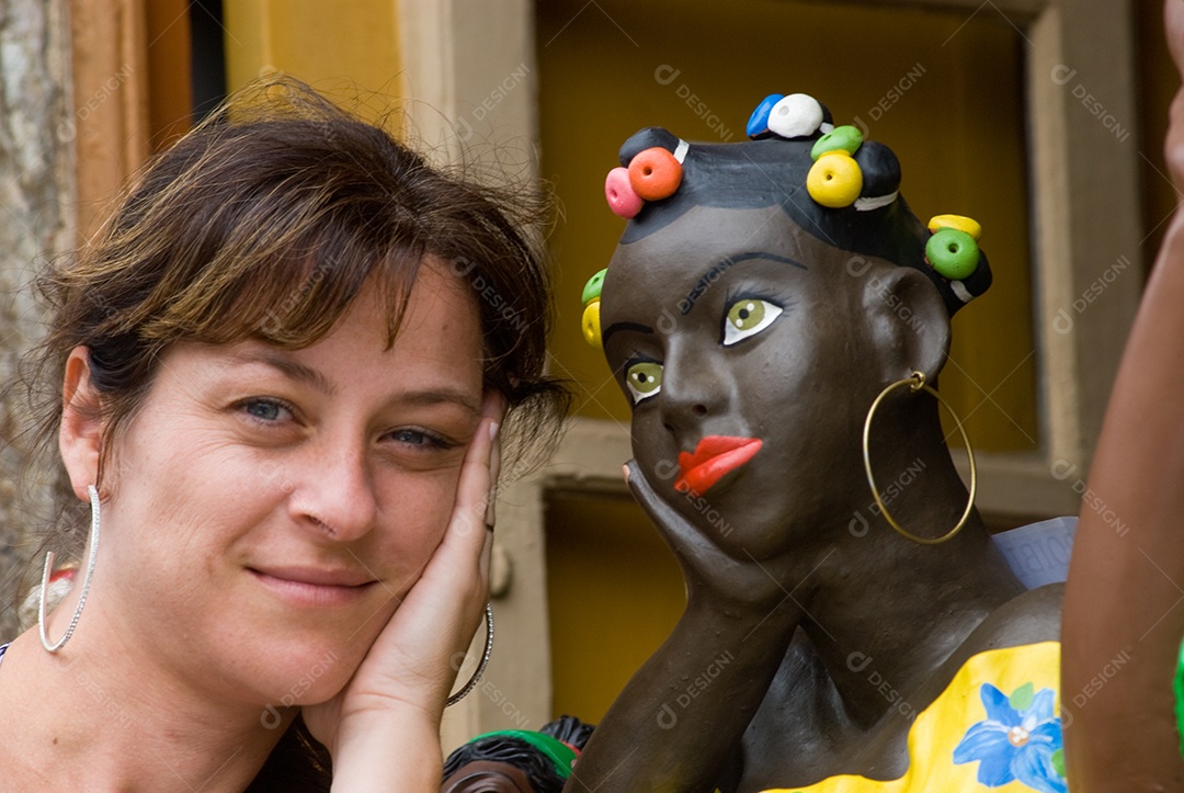 Mulher ao lado de escultura de mulher negra