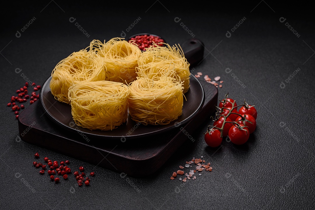 Massa crua de capellini ou macarrão com sal e especiarias sobre um fundo escuro de concreto