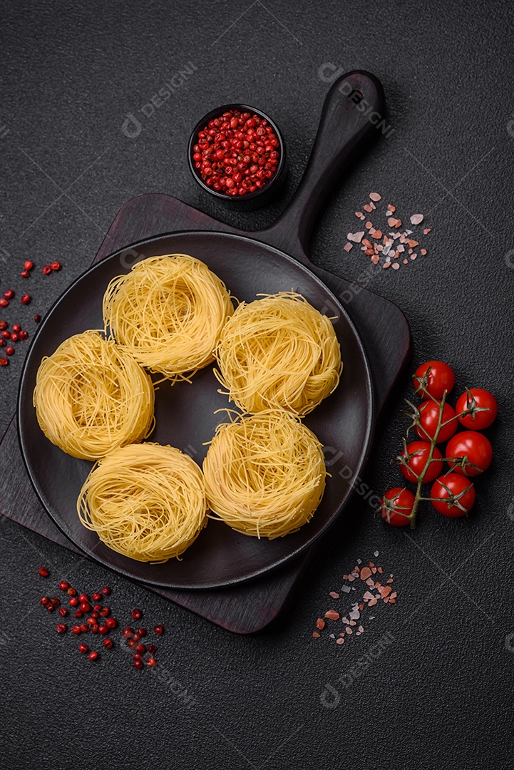 Massa crua de capellini ou macarrão com sal e especiarias sobre um fundo escuro de concreto