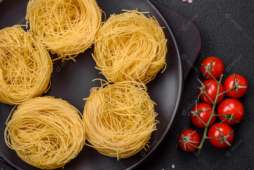 Massa crua de capellini ou macarrão com sal e especiarias sobre um fundo escuro de concreto