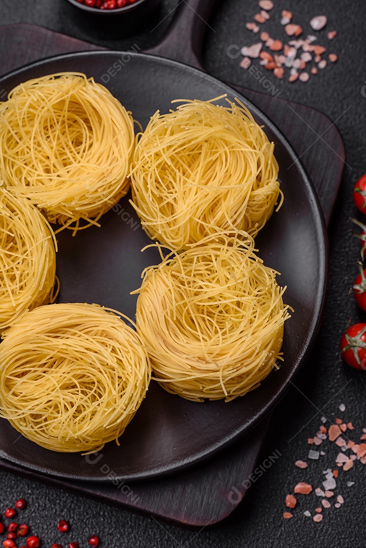 Massa crua de capellini ou macarrão com sal e especiarias sobre um fundo escuro de concreto