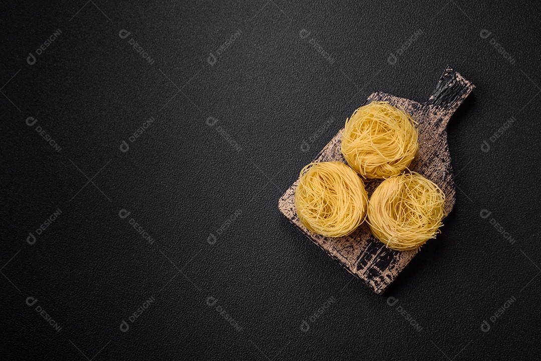 Massa crua de capellini ou macarrão com sal e especiarias sobre um fundo escuro de concreto