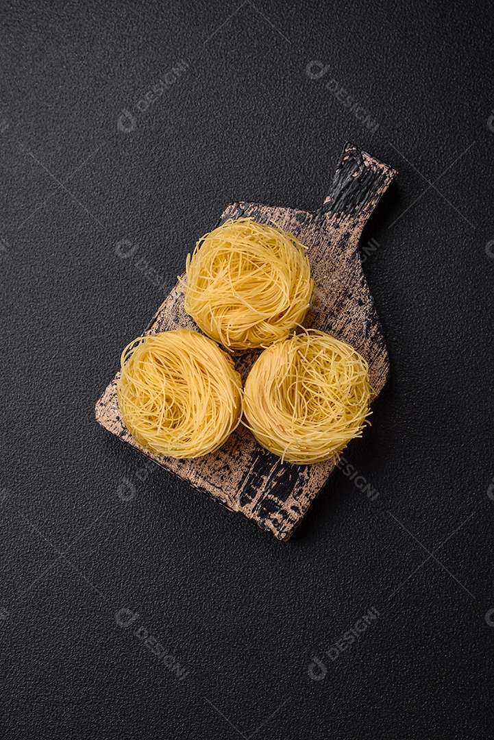 Massa crua de capellini ou macarrão com sal e especiarias sobre um fundo escuro de concreto