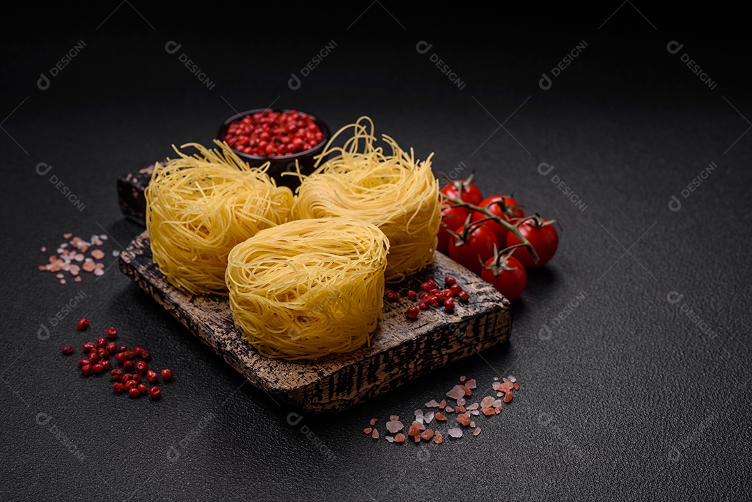 Massa crua de capellini ou macarrão com sal e especiarias sobre um fundo escuro de concreto