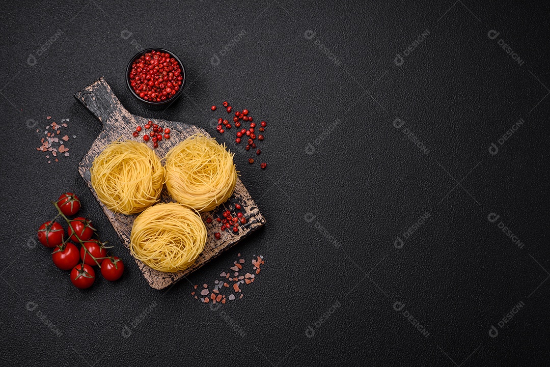 Massa crua de capellini ou macarrão com sal e especiarias sobre um fundo escuro de concreto