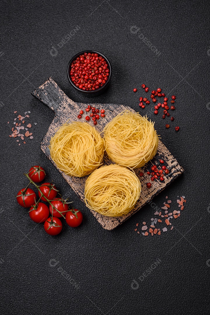 Massa crua de capellini ou macarrão com sal e especiarias sobre um fundo escuro de concreto