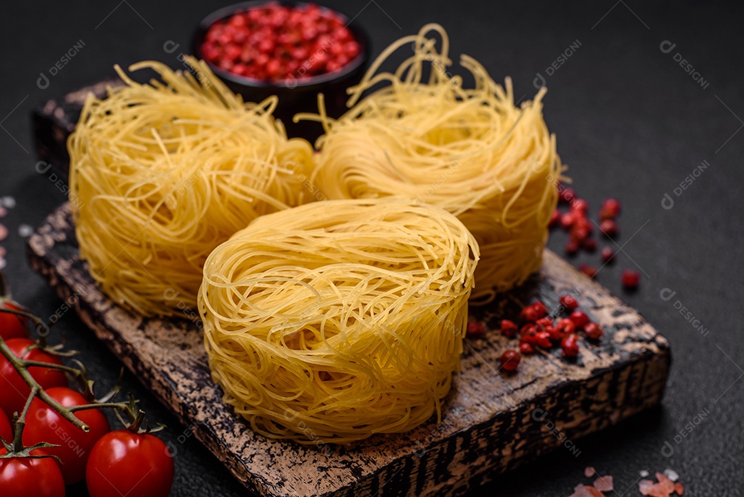 Massa crua de capellini ou macarrão com sal e especiarias sobre um fundo escuro de concreto