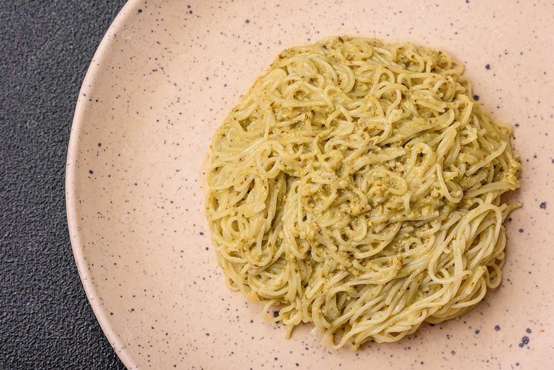 Massa Capellini ou macarrão com molho pesto, sal e especiarias sobre um fundo escuro de concreto