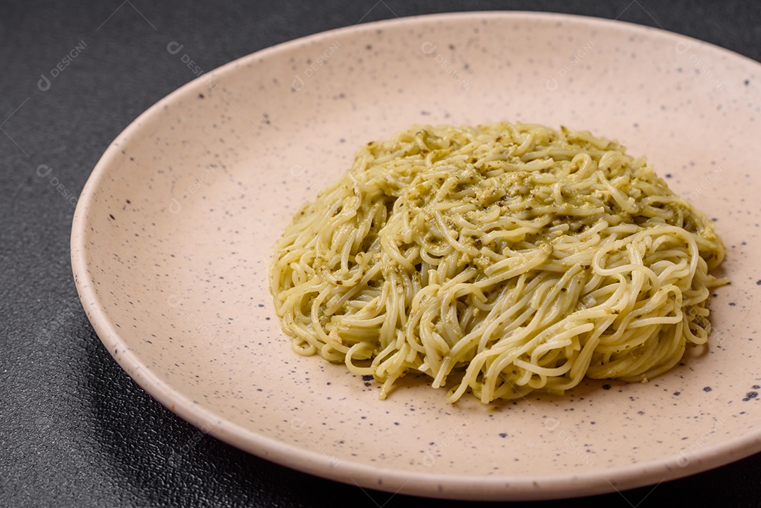 Massa Capellini ou macarrão com molho pesto, sal e especiarias sobre um fundo escuro de concreto