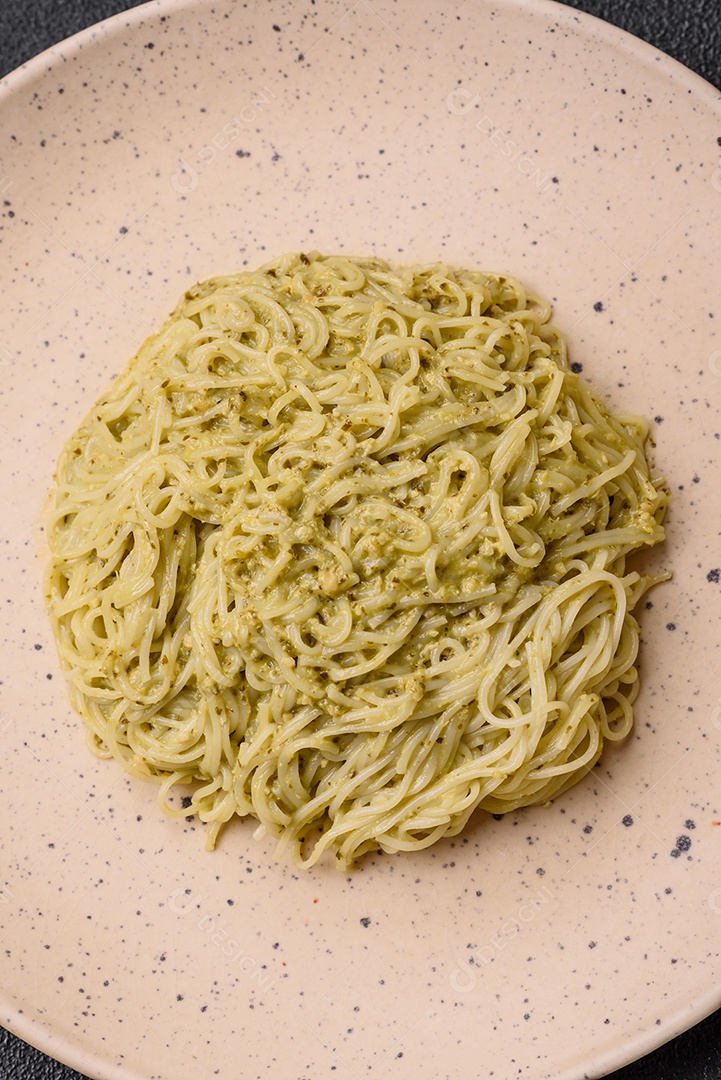 Massa Capellini ou macarrão com molho pesto, sal e especiarias sobre um fundo escuro de concreto