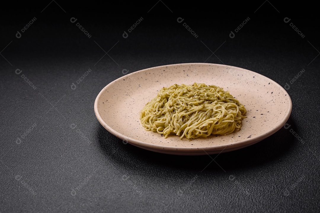 Massa Capellini ou macarrão com molho pesto, sal e especiarias sobre um fundo escuro de concreto