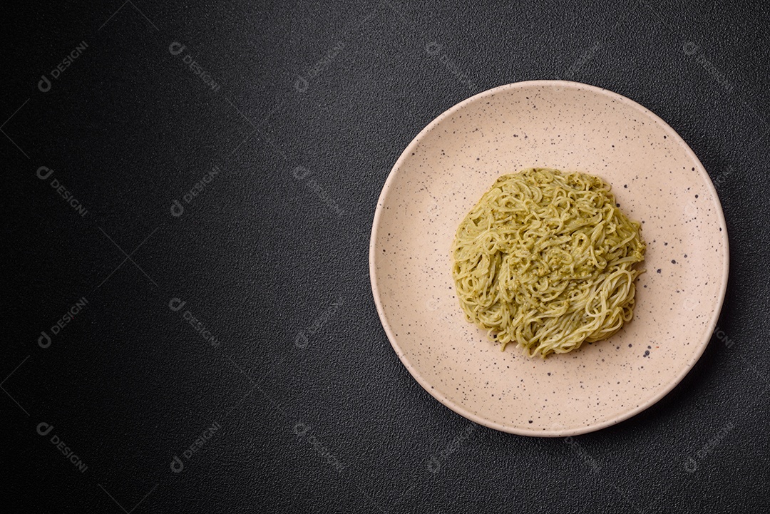 Massa Capellini ou macarrão com molho pesto, sal e especiarias sobre um fundo escuro de concreto