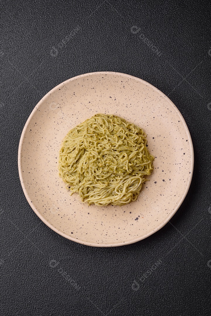 Massa Capellini ou macarrão com molho pesto, sal e especiarias sobre um fundo escuro de concreto