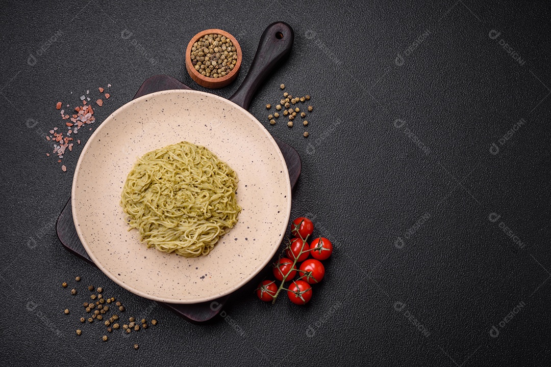 Massa Capellini ou macarrão com molho pesto, sal e especiarias sobre um fundo escuro de concreto