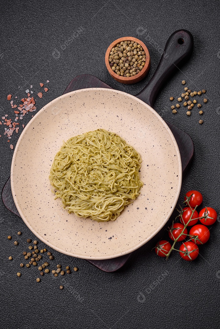 Massa Capellini ou macarrão com molho pesto, sal e especiarias sobre um fundo escuro de concreto