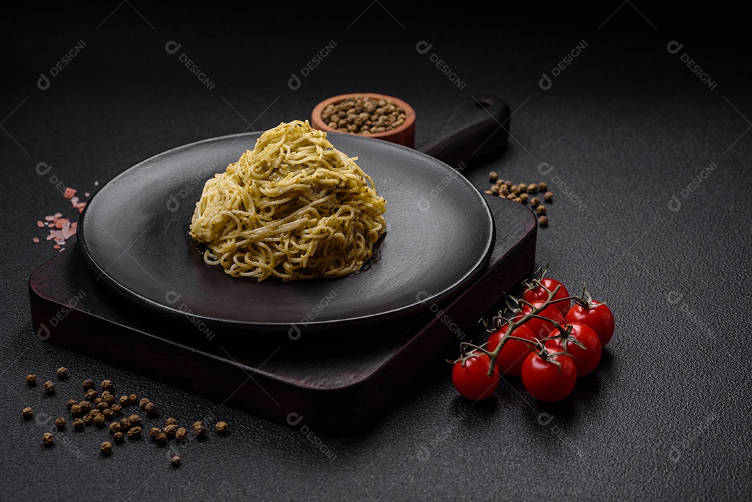 Massa Capellini ou macarrão com molho pesto, sal e especiarias sobre um fundo escuro de concreto