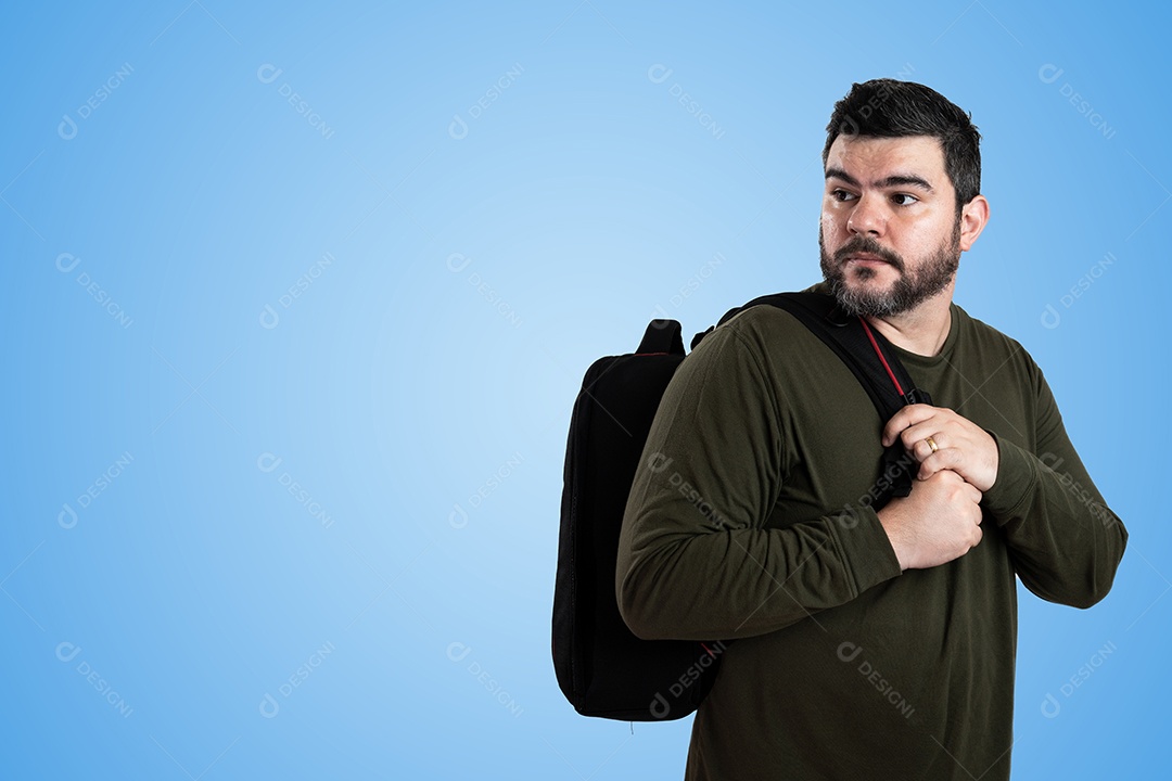 Homem barbudo feliz em pé ao ar livre com céu azul claro ao fundo.
