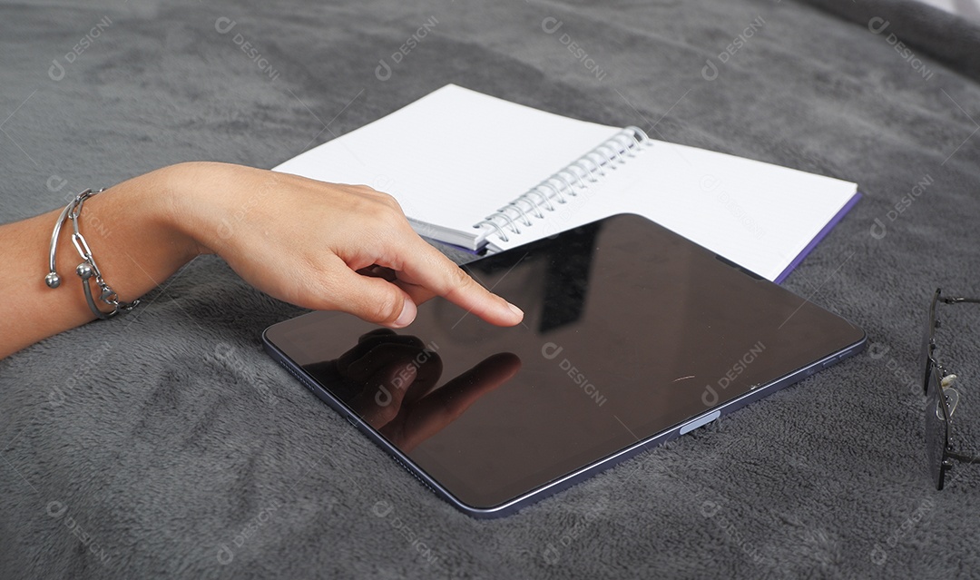 Um tablet na mesa com agenda e mão apontando