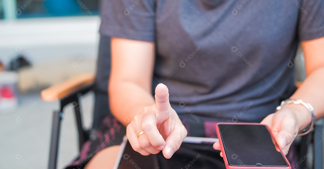 Mulher segurando nas mãos celular e um tablet no colo