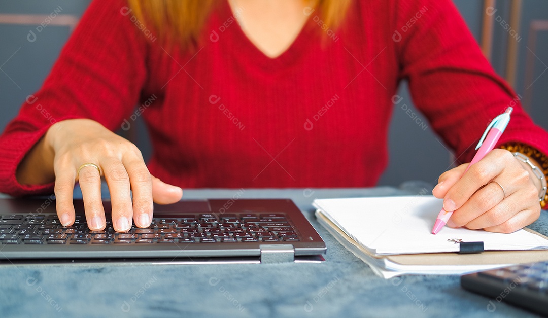 Mulher digitando trabalho no laptop e analisando dados em prancheta
