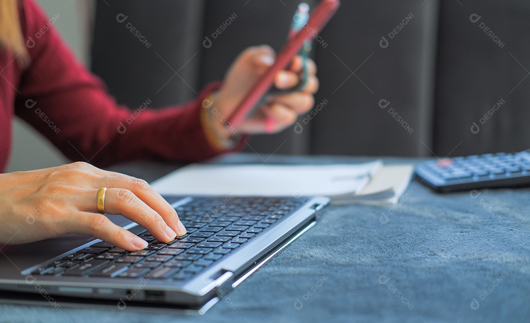 Mulher digitando trabalho no laptop e analisando dados em prancheta