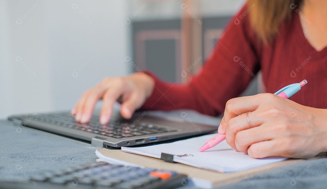 Mulher digitando trabalho no laptop e analisando dados em prancheta