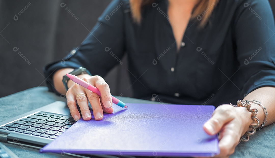 Mulher digitando trabalho no laptop com pasta nas mãos