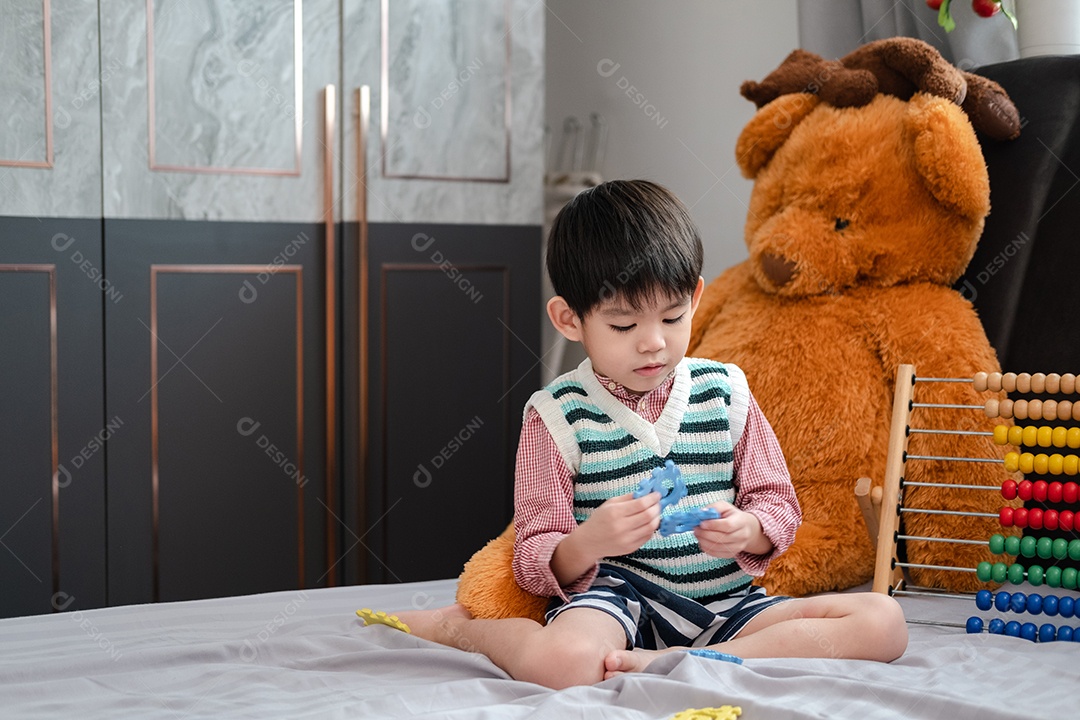 Menino asiático brincando em cima de um cama