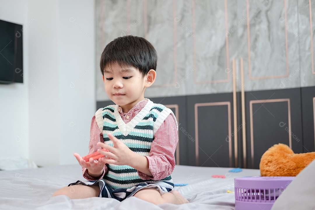 Menino asiático brincando com quebra-cabeças na cama alegremente