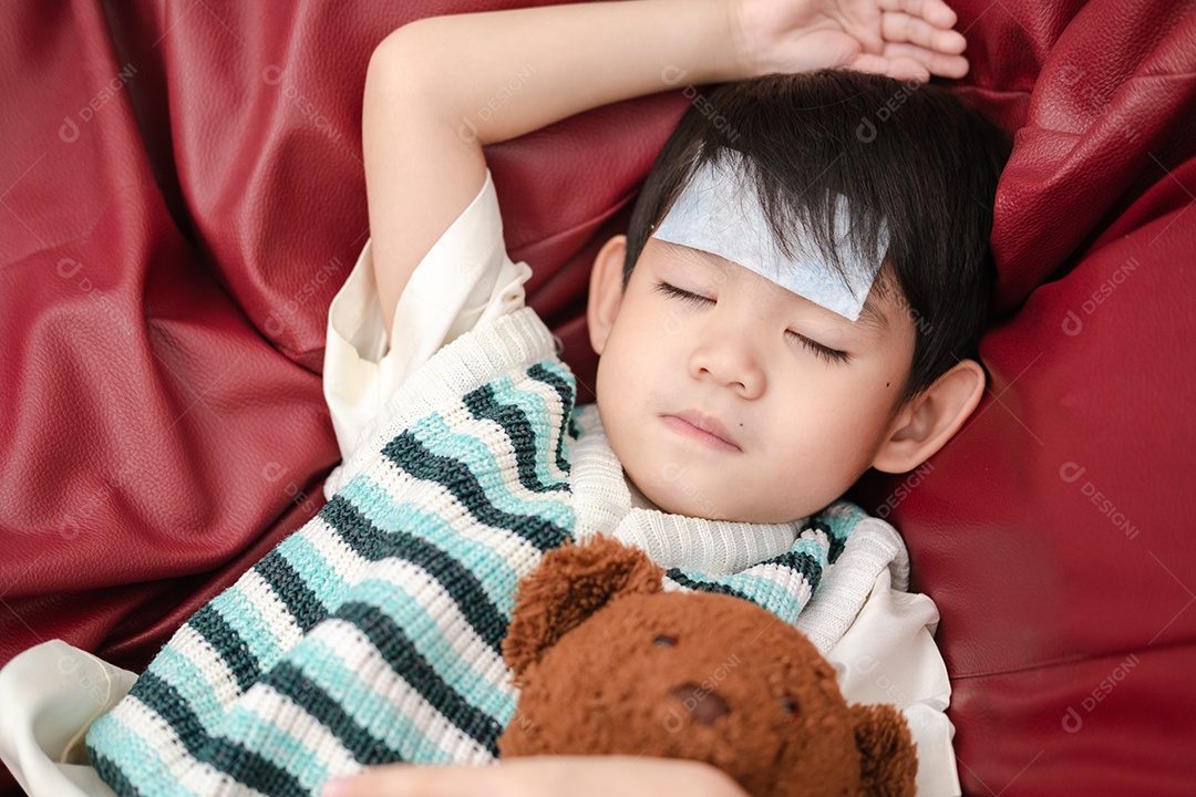 Menino asiático doente com adesivo xô-febre na testa