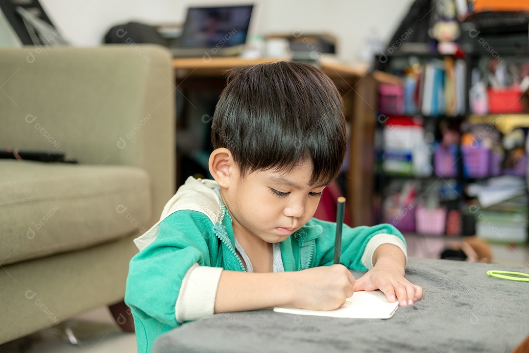 Um lindo menino desenhando  em uma folha