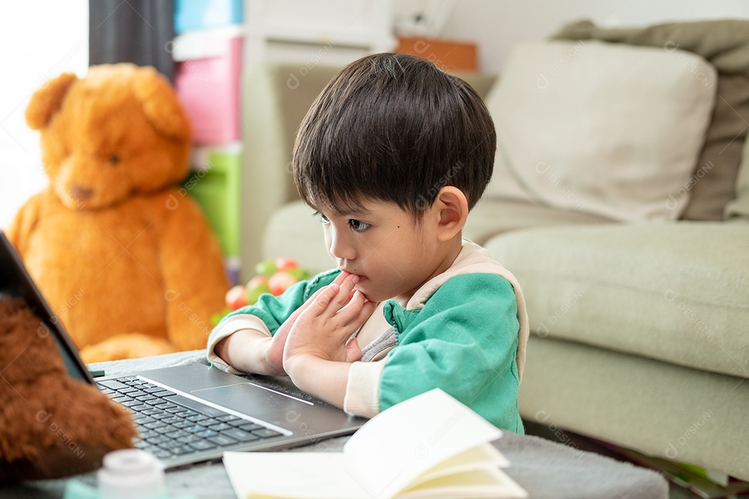 Um lindo menino asiático assistindo no laptop