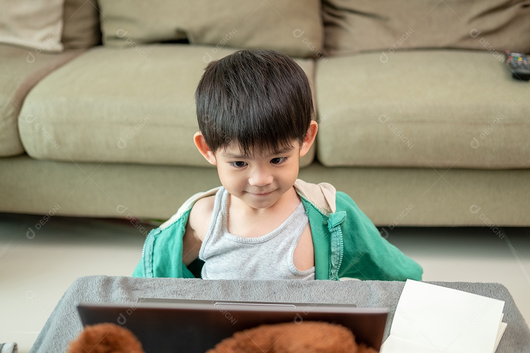 Um lindo menino asiático assistindo no laptop