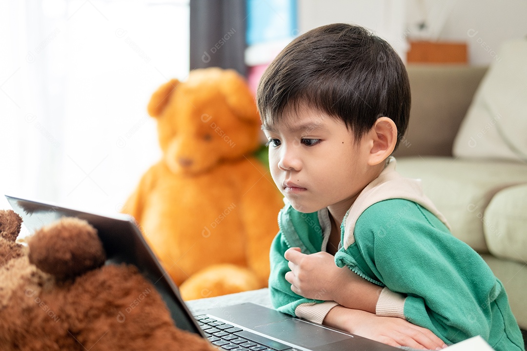 Menino asiático estudando ou assistindo no laptop