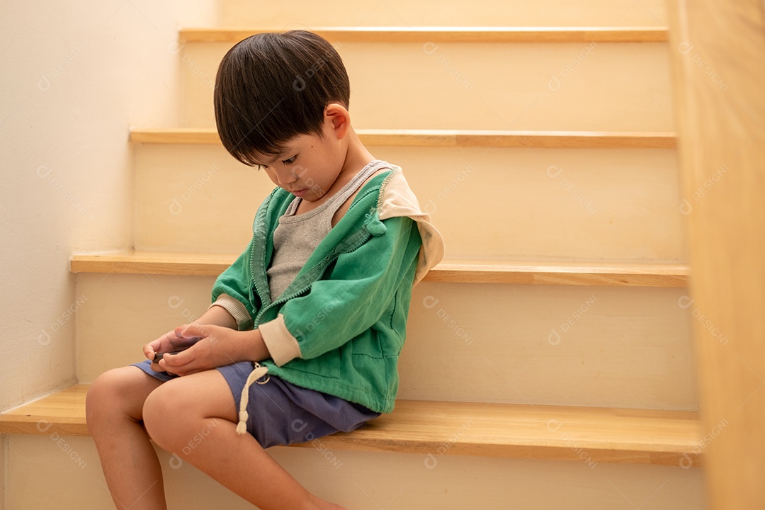 Um menino está brincando ao telefone na escada