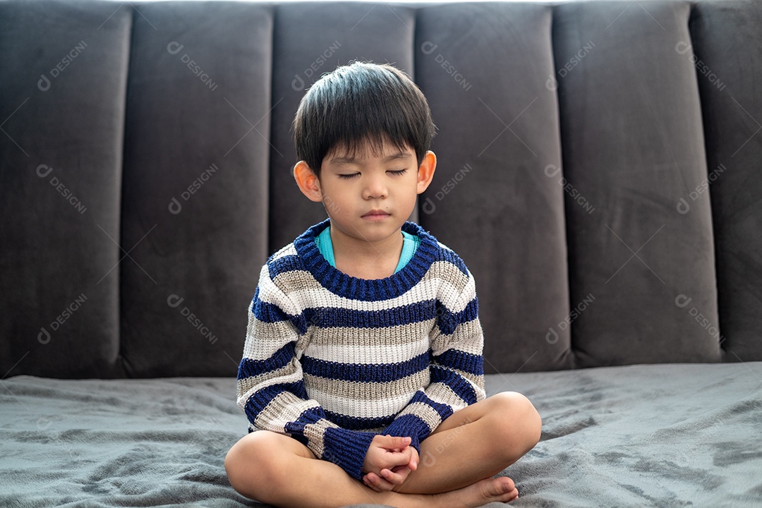 Menino asiático fazendo pose de meditação ou ioga para crianças