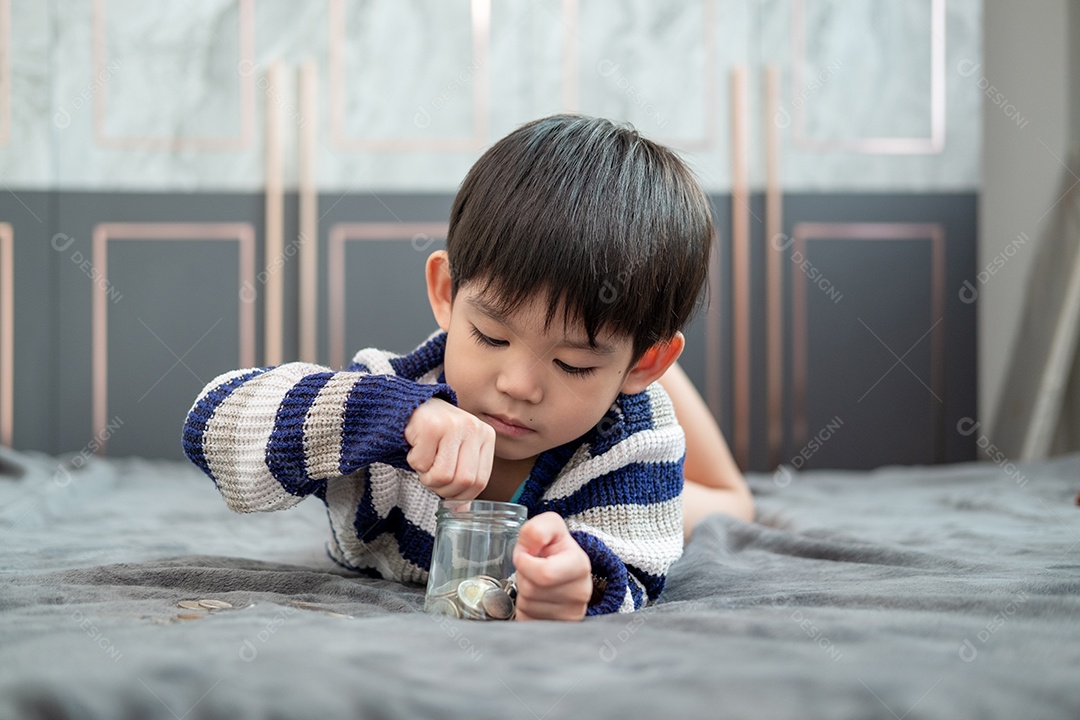 Menino colocando moedas dentro do pote de vidro