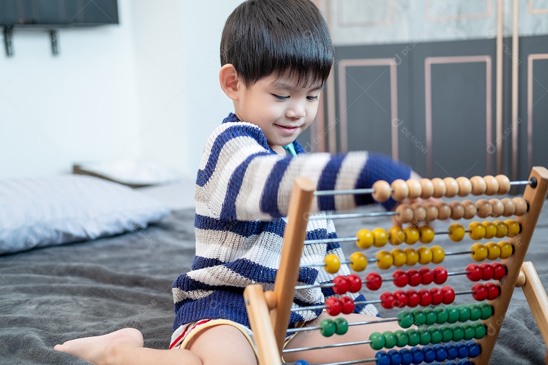 Menino asiático brincando com brinquedos na cama