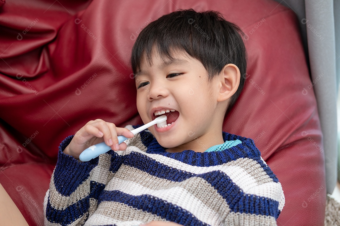 Menino asiático com escovas de dentes na boca